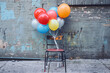 © colors - A bouquet of colorful balloons tied to a chair.