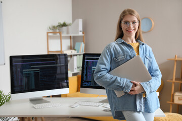 Wall Mural - Female programmer with laptop in office