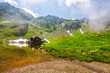 lake balea in fagaras mountains, romania. popular european travel destination in summer. grassy shore and rocky slopes on a sunny day with clouds and fog