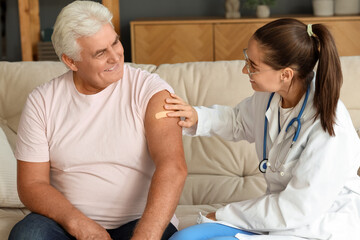 Wall Mural - Nurse putting plaster on senior man after injection at home