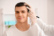 © Pixel-Shot - Doctor marking young man's head with hair loss problem in clinic, closeup