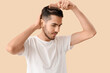 © Pixel-Shot - Young man with hair loss problem combing on beige background