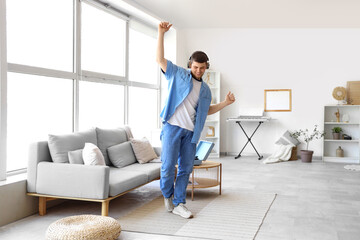 Wall Mural - Young bearded man in headphones dancing at home
