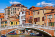 Venice, Italy. Antique stone bridge on the canal with boats and motorboats among old town italian houses. Sunny summer day. Picturesque landscape