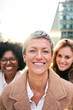 Vertical. Portrait group empowered business women of diverse ages looking smiling at camera with happy and confident expression. Caucasian attractive woman with short hair standing in foreground