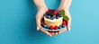 Person holding cake with berries and mint