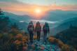 Three people are hiking up a mountain, with the sun setting behind them. Scene is peaceful and serene, as the hikers take in the beautiful scenery around themb687-549ce45e51d9