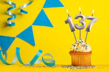 Birthday candle number 137 with cupcake - Yellow background with blue pennants