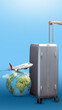 A human hand holding a suitcase with a globe and a flying airplane on a colored background. Ready for traveling