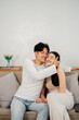 © Satori Studio - Cheerful couple sharing a warm embrace, smiling and enjoying each other's company on a comfortable couch at home.