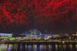 Night illumination of the city, tree branches illuminated in red. Night view of Moscow city and the river from the Rostov embankment of the Moscow River.