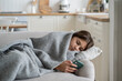 Unhappy offended teenage girl lying on couch with smartphone after difficult school day following publications of friends in social networks. Depressive weakened schoolgirl uses mobile phone at home