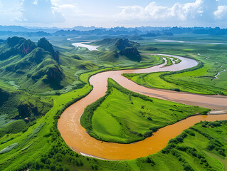 Wall Mural - A river winds through a grassy valley with rolling hills and mountains in the background.