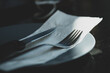 Metal knife and fork on a tissue paper and dish on a wooden table. Near white dishes. The concept of food
