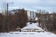 View of a snow-covered road and a collapsed bridge. Residential buildings in the distance. The bridge collapsed as a result of summer floods in 2022. Tynda, Amur region, Russia - January 22, 2024.
