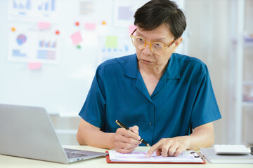 business idea Elderly male businessman working at home or in the office Graph showing annual income Male analyst sitting and working at a table in the office.