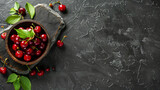 Board with bowl of sweet cherries on black table
