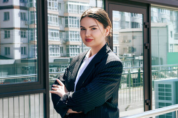 A business woman in a jacket stands against the backdrop of a business center6