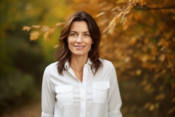 Sticker - Portrait of a happy woman in her 30s wearing a simple cotton shirt in background of autumn leaves