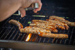 saucisses en cuisson sur une grille de barbecue, avec des flammes attisées par la graisse.