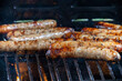 saucisses en cuisson sur une grille de barbecue, avec des flammes attisées par la graisse.