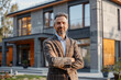 Portrait of a male realtor standing in front of a modern house