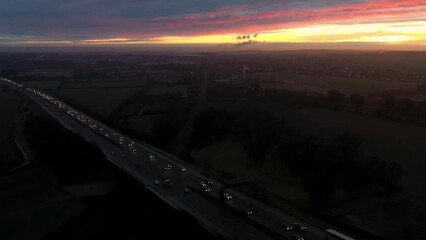 Canvas Print - Aerial footage of the town of Garforth in Leeds UK overlooking the motorway at sunset with cars driving on the road while the sun sets in the background