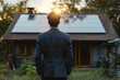 A man in a suit standing in front of a small house with solar panels on the roof during sunset