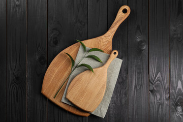 Wall Mural - Cutting boards, green branch and napkin on black wooden table, top view