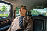 Fototapeta Sawanna - Relaxing moment of mature man sleeping in car back seats with safety belt. old man happy in car while traveling on the road to destination.