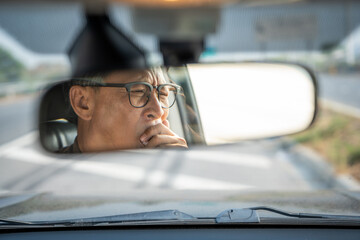 Rear view mirror. Senior asian man driver was drowsy. Mature old man yawned and was about to fall asleep Doze off Driving for a long time sleep deprivation