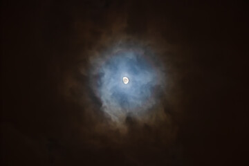 Wall Mural - The Moon is surrounded by colorful glowing clouds in the dark night sky. Night sky scene