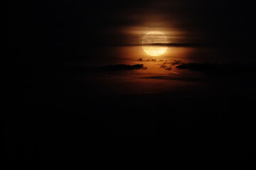 Wall Mural - Full Moon in dark clouds against a black sky. Natural night sky scenery