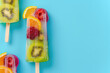 frame of multicolored fruit ice on a stick, on a blue, summer background