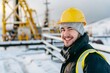 © senyumanmu - Smiling young engineer wearing hardhat at oil production field in winter