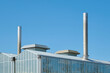 Roof of an industrial greenhouse with chimneys against a blue sunny sky. Image with copy space