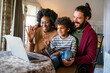 Happy multiethnic diverse family gathering around notebook and having fun during a video call