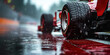 rear wheel of red racing car at start of race in rain on wet slippery asphalt