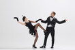 © master1305 - Stylish couple reenacts 1920s dance, woman in fringe dress and man in dapper black suit dancing isolated over white studio background. Concept of art, retro and vintage, hobby, entertainment, 20s