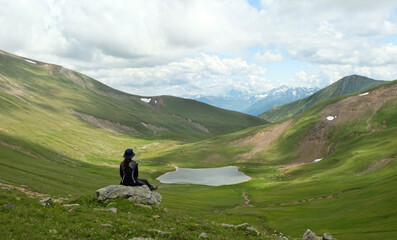 beautiful Summer landscape with sitting relaxing tourist in mountains. rear view. scenic nature view. adventure atmosphere. travel lifestyle. trip, journey, hiking concept.