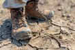 Close-up of a hikers boots, showcasing the dusty trail, cracked earth, and determined stride
