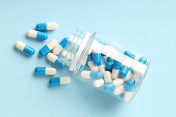 Wall Mural - Antibiotic pills and bottle on light blue background, top view