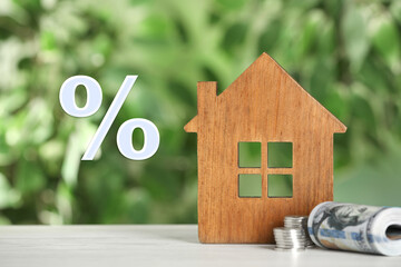 Wall Mural - Mortgage. Wooden house model, money and percent sign on blurred green background