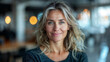 © Filirovska - Mature woman with wavy hair smiling in a modern office