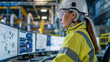 © AdamDiezel - person in an industrial environment, wearing a white safety helmet and a high-visibility jacket, is interacting with multiple computer monitors that display a variety of data