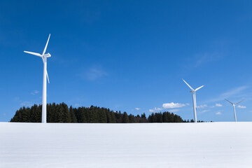 three wind turbines in snow surroundings are on the mountain