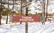 Think positive symbol. Concept words Think positive on beautiful wooden road sign. Beautiful forest snow blue sky background. Business, motivational think positive thinking concept. Copy space.
