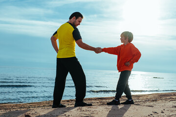 Poster - Father and son shaking hands on lake shore at sunny day