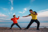 Fototapeta Sypialnia - Father and son martial arts training on lake shore