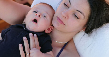 Canvas Print - Baby on top of mother yawning looking to camera